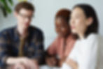 Three creatives in discussion sitting around a table.